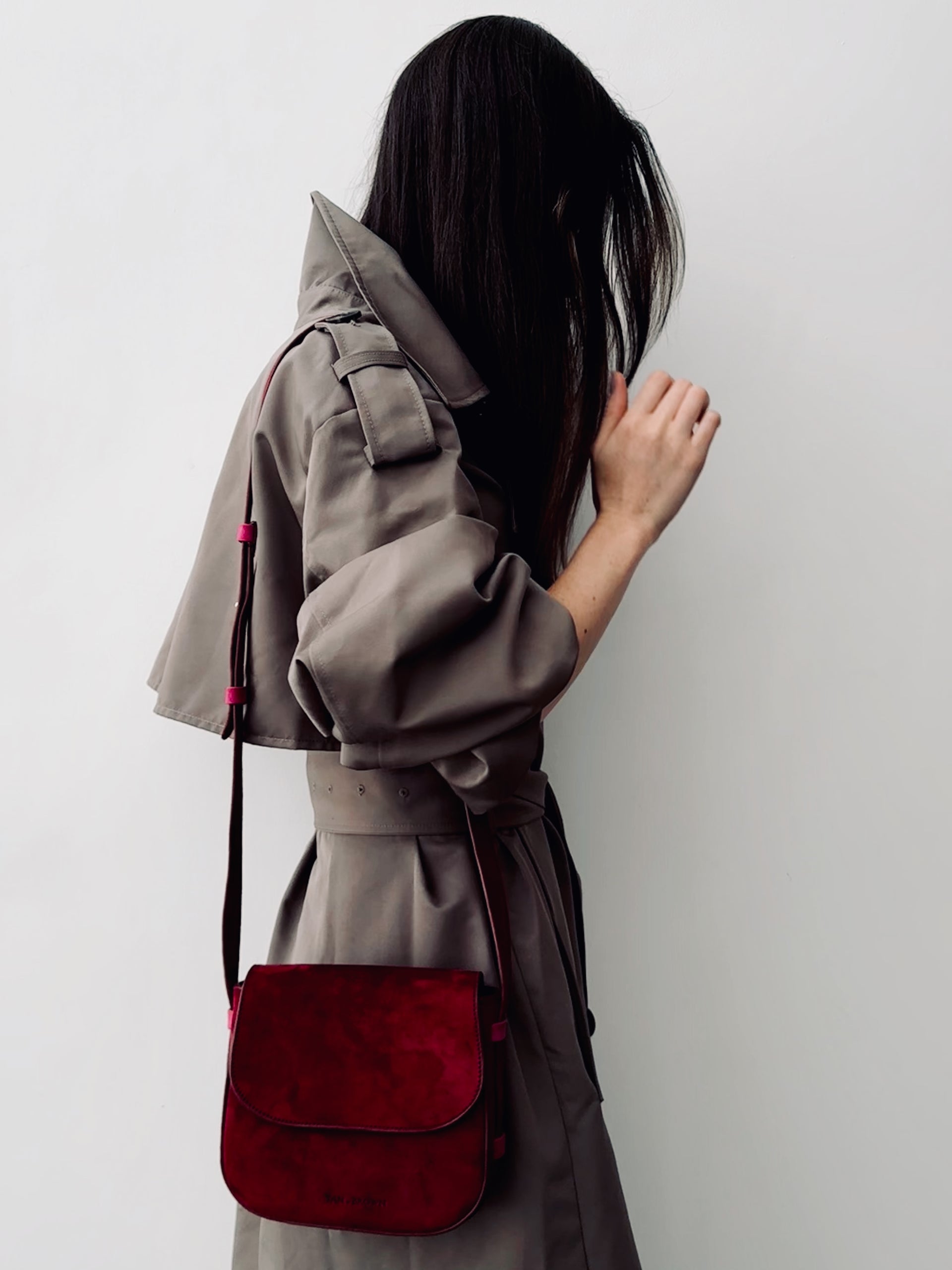 Person wearing a gray coat with a red bag against a white background