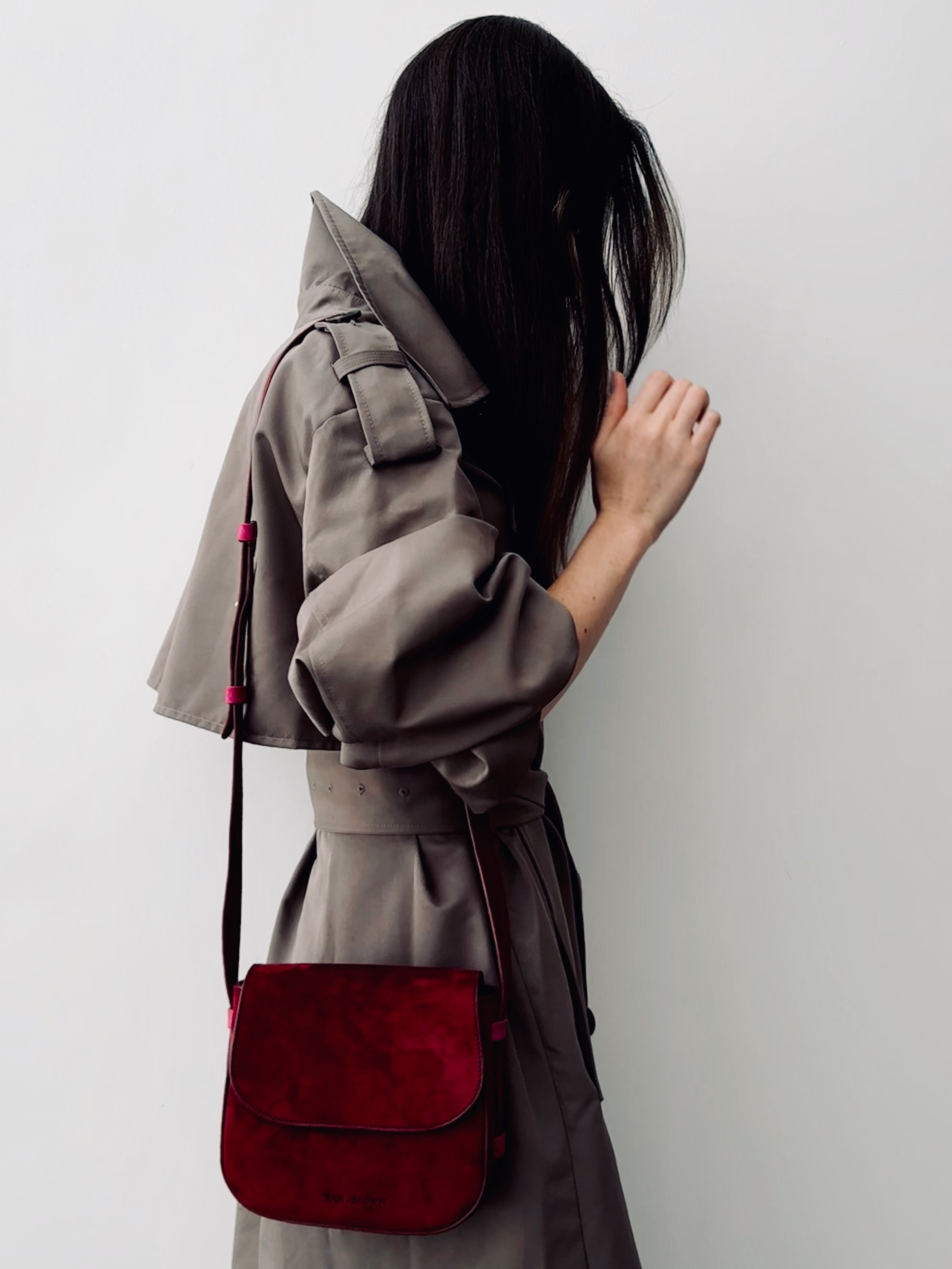 Person wearing a gray coat with a red bag against a white background