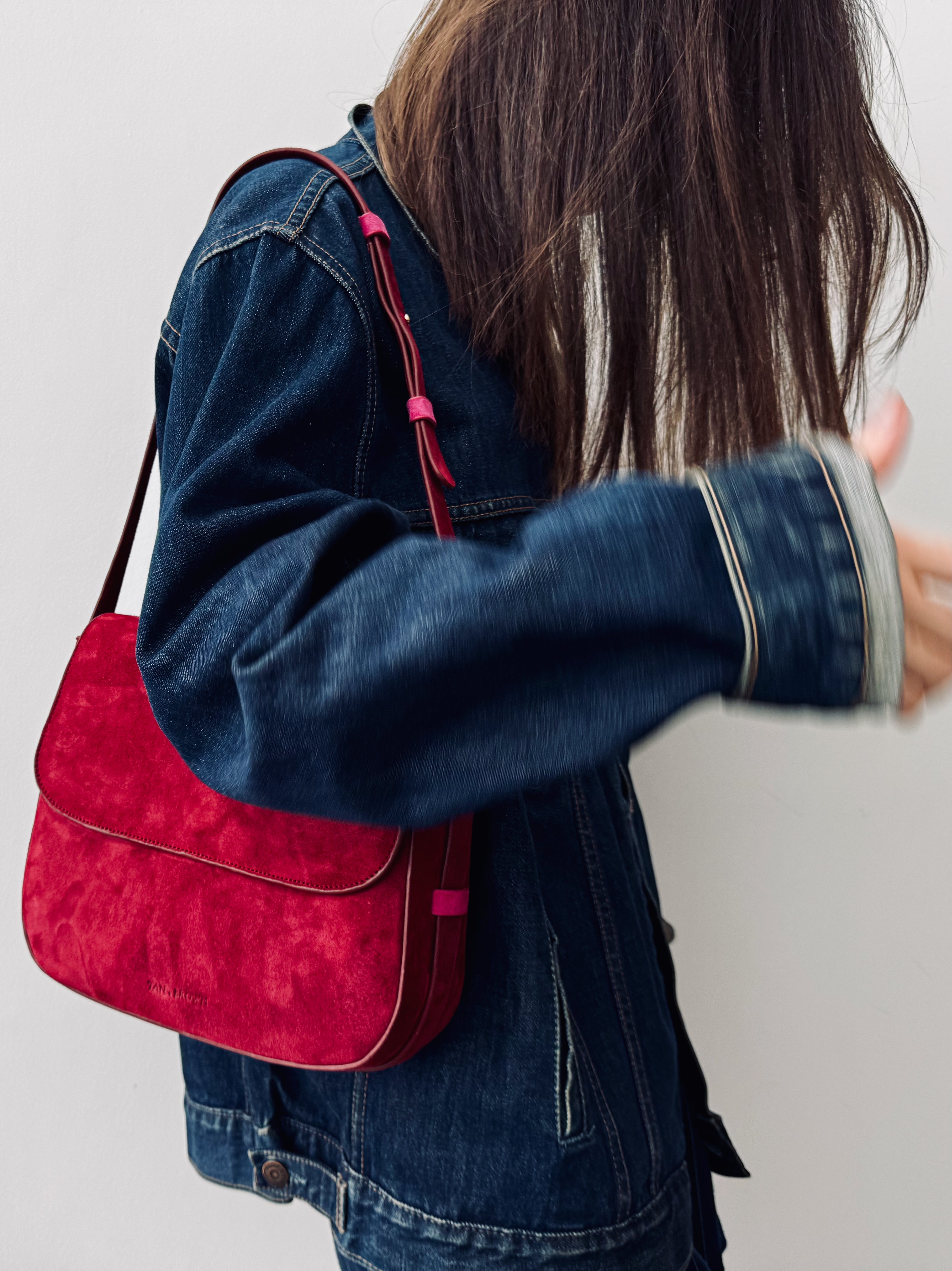 Person wearing a red and black bag over their shoulder against a plain background