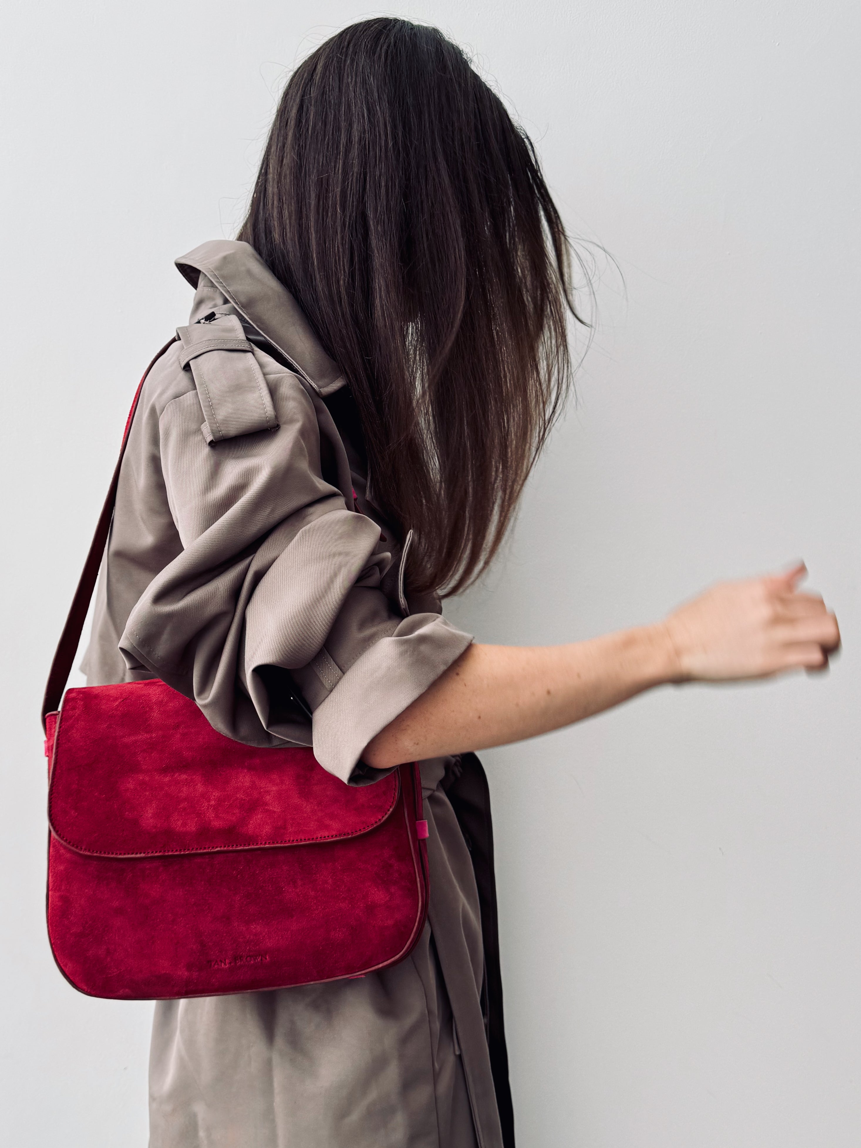 Person wearing a red bag over their shoulder against a plain background